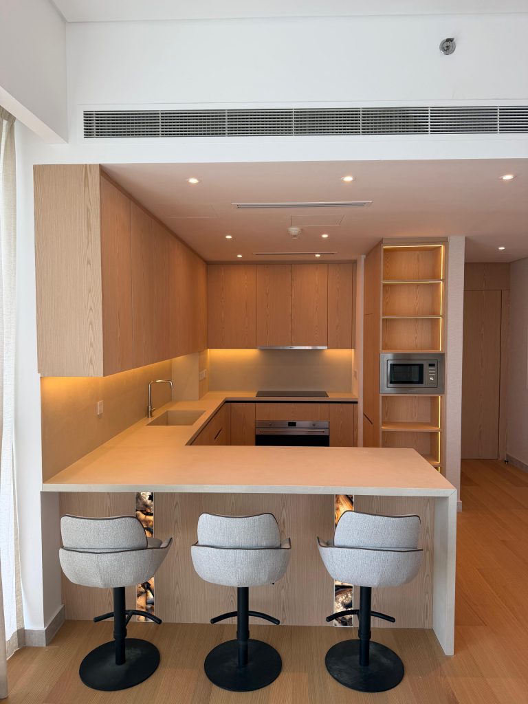 Home 4 Timber kitchen with a backlit agate peninsula and bar stools in a Canal Front apartment, Dubai