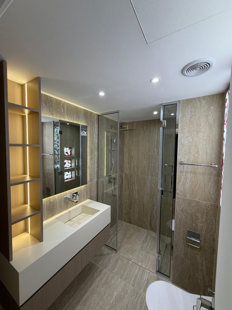 Bathroom Renovation Dubai 2 Bathroom vanity with backlit shelving, stone counter and glass shower at Canal Front CF09