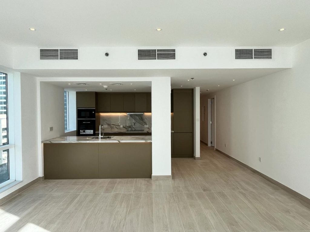 Open-plan kitchen and living area with a handleless peninsula and timber-look flooring