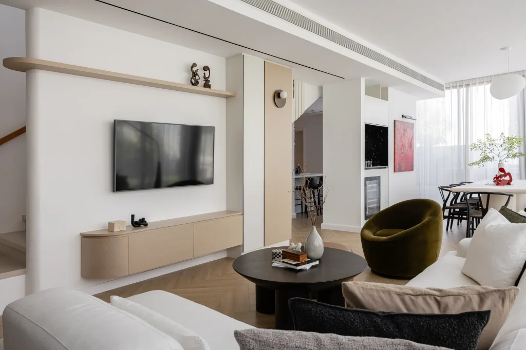 Projects We Have Done 13 Living room with a TV wall, pale rounded cabinetry and a display shelf.
